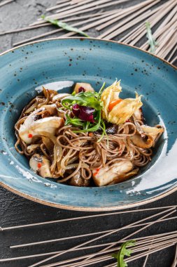 Tatlı ve ekşi sos, soğan ve plaka karanlık taş zemin üzerine yeşil yabani mantar ile soba erişte. Vejetaryen yiyecekler