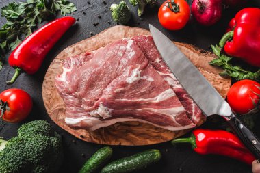 Çiğ et, sığır eti biftek yemek pişirmek için malzemeler siyah zemin üzerine bıçakla kesme tahtası üzerinde. Üstten görünüm