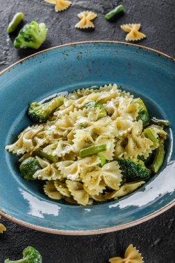 Vegan Farfalle makarna ıspanak soslu brokoli, Brüksel lahanası, plaka karanlık taş zemin üzerine yeşil fasulye ile. Üstten görünüm, düz yatıyordu. Vejetaryen yiyecekler