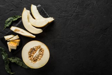 Siyah taş zemin üzerine sarı kavun. Renkli taze meyve. Üstten görünüm, düz yatıyordu, kopya alanı