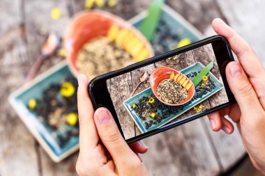 Kızın eller fotoğraf yulaf lapası ayçiçeği tohumu, susam ve şeftali ile smartphone tarafından çekici. Sağlıklı Kahvaltı, temiz yemek, vegan gıda kavramı
