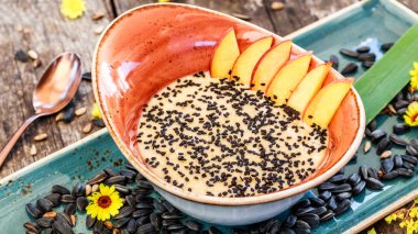 Ayçiçeği tohumu, susam ve parlak ahşap masa üzerinde şeftali ile yulaf lapası. Seçici odak. Sağlıklı Kahvaltı, vegan gıda