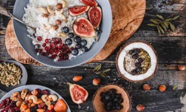 Pilav Hindistan cevizi yulaf lapası incir, çilek, fındık, Kuru kayısı ve plaka rustik ahşap zemin üzerine Hindistan cevizi sütü ile. Sağlıklı kahvaltı malzemeler. Temiz yemek, vegan gıda kavramı, üstten görünüm