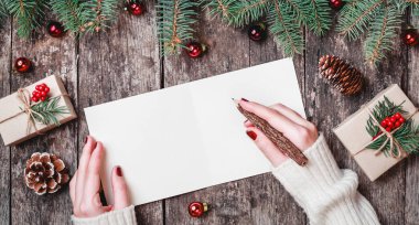 Noel hediyeleri, çam dalları ve şeker ile ahşap arka plan üzerinde Noel Baba'ya bir mektup okuma ve yazma el. Noel ve mutlu yeni yıl kompozisyon. Düz yatıyordu, en iyi görünümü