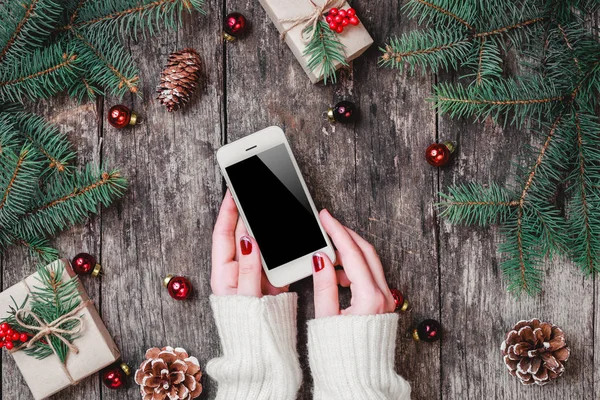 Kvinnliga Händer Som Håller Mobiltelefon Trä Bakgrund Med Julklappar Grenar — Stockfoto