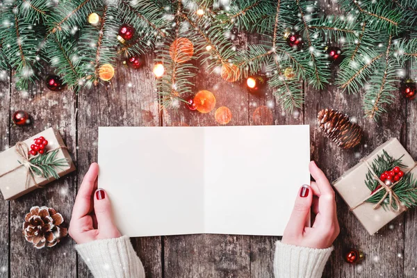 女性の手を書くと木製の背景にクリスマス プレゼント モミの枝 お菓子をサンタさんへ手紙を読みます クリスマスと新年あけましておめでとうございますの組成物 フラット横たわっていた トップ ビュー — ストック写真