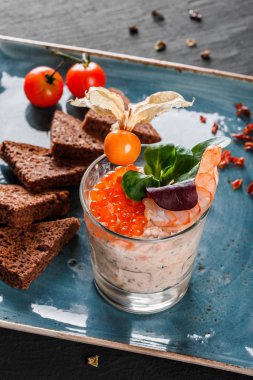 Karides ve kırmızı havyar physalis ve Yeşiller plaka üzerinde süslenmiş siyah arka plan üzerinde siyah ekmek ile snack. Sağlıklı gıda