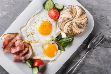 Kahvaltı, sahanda yumurta, topuz, pastırma, salam, plaka gri masa yüzeyi üzerinde taze salata. Sağlıklı gıda