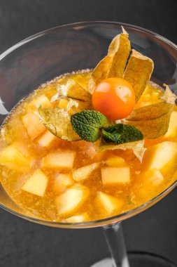 Mango ve Şeftali meyve jöle nane ve karanlık taş zemin üzerine bir bardak physalis süslenmiş. Yaz tatlı
