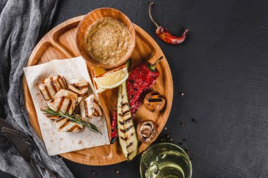 Izgara fileto balığı ve baharat soslu sebze siyah taş arka planda tahtayı kesiyor. Sıcak balık tabakları. Üst manzara, düz uzanma