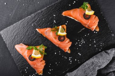 Somon fileto, zeytin ve limon ciabatta ekmeği taş arduvaz arka plan üzerinde üzerinde meze bruschetta. Sağlıklı gıda kavramı, üstten görünüm, düz yatıyordu