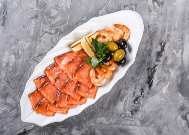 Deniz ürünleri tabağı dilim somon, karides, dilimleri ile balık fileto, rustik arka plan üzerinde zeytin ve limon plaka süslenmiş. Akdeniz meze. Üstten görünüm