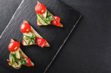 Meze bruschetta sebze, domates ve baharat siyah şeyl üzerinde siyah taş zemin kurulu. Sağlıklı gıda kavramı, üstten görünüm, düz yatıyordu