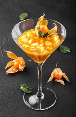 Mango ve Şeftali meyve jöle nane ve karanlık taş zemin üzerine bir bardak physalis süslenmiş. Yaz tatlı