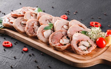 Çeşitli et, tavuk dolması rulo, et rulo ile biber, yeşillik siyah şeyl arka plan üzerinde kesme tahtası üzerinde. Et iştah açıcı, gıda kavramı