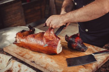 Şef ızgara kesme elinde bıçakla kesme tahtası üzerinde domuz biftek için ızgara. Sıcak et yemekleri