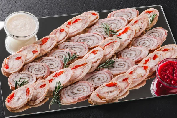 Assorted meat, stuffed chicken roll, meat roll with pepper, greens on black shale background. Meat appetizer, food concept. Top view, flat lay