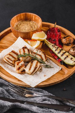 Izgara fileto balık ve sebze kesme tahtası üzerinde siyah taş zemin üzerine baharat soslu. Sıcak balık yemekleri