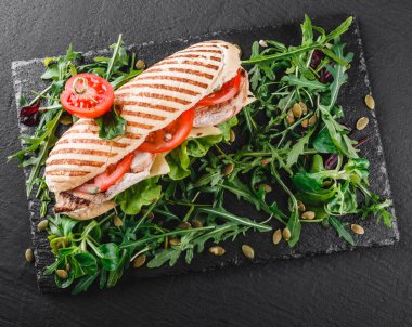 Sandviç fileto ızgara tavuk, taze sebze, peynir ve Yeşiller siyah taş zemin üzerine siyah şeyl gemide. Sağlıklı gıda kavramı. Üstten görünüm, düz yatıyordu