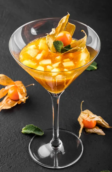 Mango ve Şeftali meyve jöle nane ve karanlık taş zemin üzerine bir bardak physalis süslenmiş. Yaz tatlı