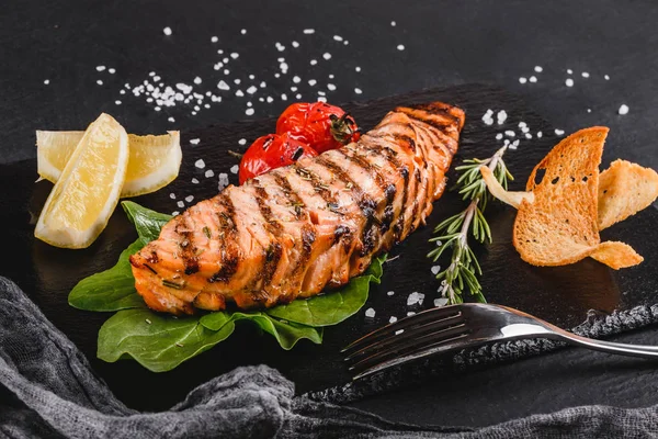 木製の背景にほうれん草 レモン ハーブでのプレートを添えて焼き鮭 ホット魚料理 — ストック写真