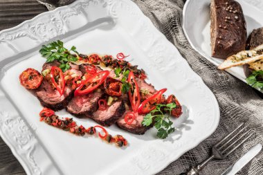 Sulu orta sığır filetosu biftek mignon ile biber, baharatlar plaka rustik ahşap zemin üzerinde. Sıcak et yemekleri. Üstten görünüm