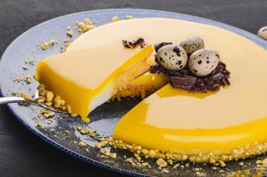 Sarı ayna sır, çikolata, bahar çiçekleri, karanlık taş zemin üzerine bıldırcın yumurtası ile Paskalya kek. Mutlu Paskalya kutlamaları.