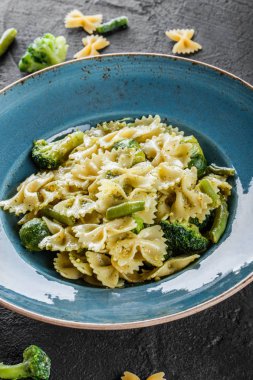 Vegan Farfalle makarna ıspanak soslu brokoli, Brüksel lahanası, plaka karanlık taş zemin üzerine yeşil fasulye ile. Üstten görünüm, düz yatıyordu. Vejetaryen yiyecekler