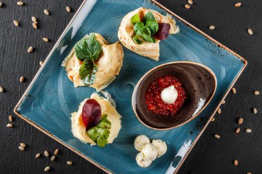 Doldurulmuş Krep kırmızı havyar, tereyağı ve Yeşiller plaka ile tepesinde. Bir koyu gri taş yüzeye görüntüleyin. Krep hafta ya da Shrovetide. Sağlıklı kahvaltı. Üstten Görünüm, düz yatıyordu