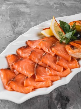 Deniz ürünleri tabağı dilim somon, karides, dilimleri ile balık fileto, rustik arka plan üzerinde zeytin ve limon plaka süslenmiş. Akdeniz meze