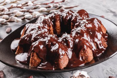 Paskalya kek çikolata, Hindistan cevizi, bir taş zemin üzerine bahar çiçekleri ile. Mutlu Paskalya kutlamaları