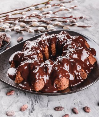 Paskalya kek çikolata, Hindistan cevizi, bir taş zemin üzerine bahar çiçekleri ile. Mutlu Paskalya kutlamaları