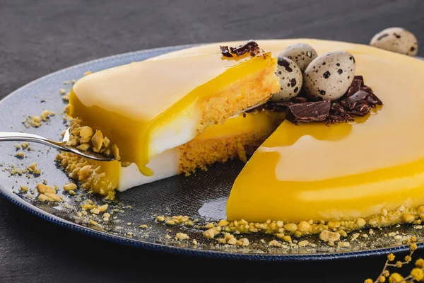 Bolo de Páscoa com esmalte espelho amarelo, chocolate, flores da primavera, ovos de codorna no fundo de pedra escura. Feliz celebração da Páscoa . — Fotografia de Stock