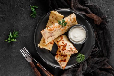 Kıyılmış et, yeşil ve koyu arka plan üzerinde siyah plaka üzerinde ekşi krema ile krep. Krep hafta ya da Shrovetide. Sağlıklı kahvaltı. Üstten Görünüm, düz yatıyordu