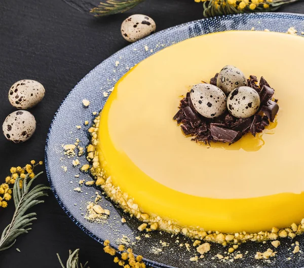 Påsk kaka med gul spegel glasyr, choklad, vårblommor, vaktelägg på mörk sten bakgrund. Glad påskfirande. — Stockfoto