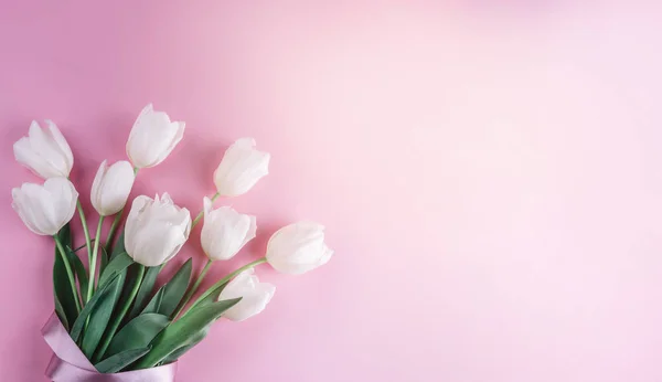 Strauß weißer Tulpenblüten auf rosa Hintergrund. Karte für Muttertag, 8. März, frohe Ostern. Warten auf den Frühling. Grußkarte oder Hochzeitseinladung. flache Lage, Draufsicht — Stockfoto
