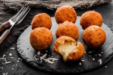Kızarmış patates peynir topları veya taş koyu arka plan üzerinde siyah plaka üzerinde baharatlar ile kroket. Sağlıksız yiyecek.