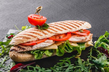 Sandviç fileto ızgara tavuk, taze sebze, peynir ve Yeşiller siyah taş zemin üzerine siyah şeyl gemide. Sağlıklı gıda kavramı. Üstten görünüm, düz yatıyordu