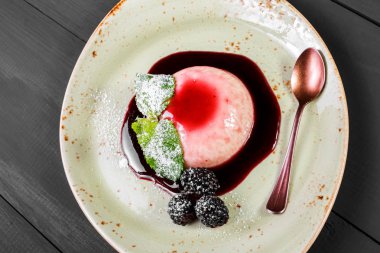 İtalyan tatlı panna cotta plaka üzerinde böğürtlen reçeli ve nane ile dekore edilmiştir. Üstten Görünüm.