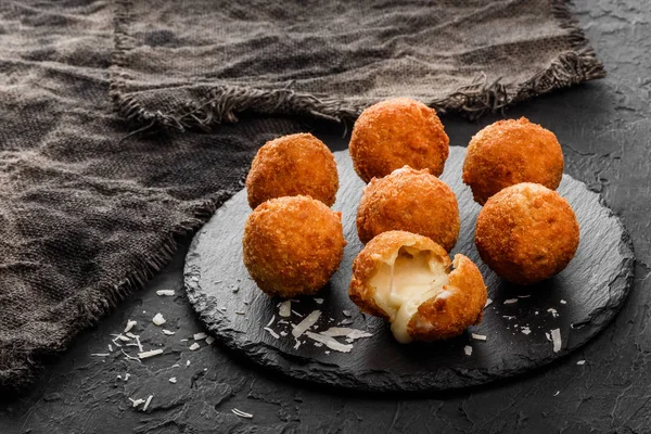 Bolinhas de queijo de batata frita ou croquetes com especiarias na placa preta sobre fundo de pedra escura. Alimentos não saudáveis . — Fotografia de Stock