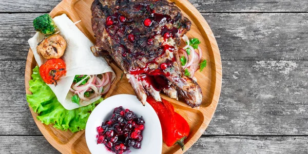 Grilovaná Ribeye Steak na kosti s berry omáčka, čerstvý salát a grilované zeleniny na prkénku na dřevěné pozadí zblízka. Horká masová jídla — Stock fotografie