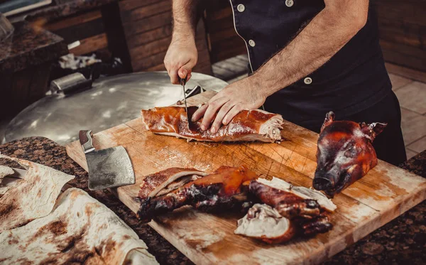 Chef Mãos cortando porco grelhado grelhado para bifes com faca na tábua de corte. Pratos de carne quente . — Fotografia de Stock