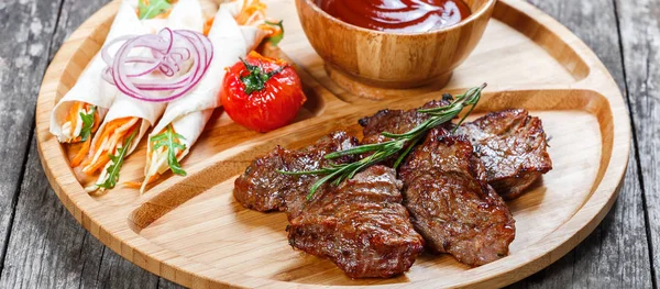 구운된 쇠고기와 신선한 샐러드와 나무 배경 절단 보드에 바베 큐 소스와 야채 닫습니다. 뜨거운 고기 요리입니다. 상위 뷰 — 스톡 사진