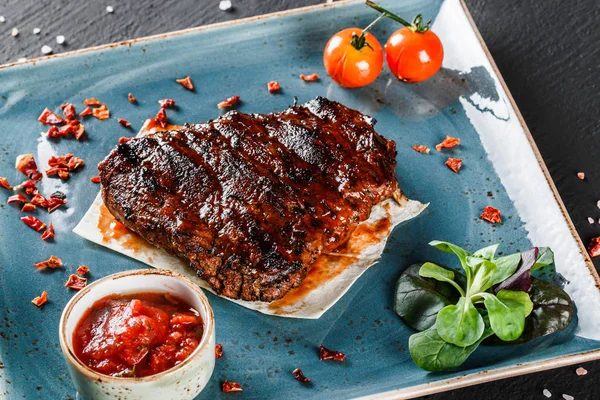 Grilovaný masový steak a Rajská omáčka na tmavém kamenném pozadí. Teplá masová jídla. — Stock fotografie
