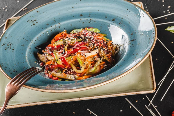 Pasta de espaguetis con salsa, verduras estofadas y semillas en plato en la mesa de piedra oscura.Fideos vegetarianos, comida italiana . — Foto de Stock