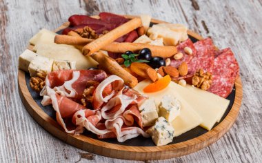 Antipasto plakalı soğuk et Grissini ekmek çubukları, Prosciutto, dilim jambon, sığır eti, salam ve peynir tabağı ahşap tahta üzerinde rustik arka plan üzerinde. Aperitif, catering gıda kavramı