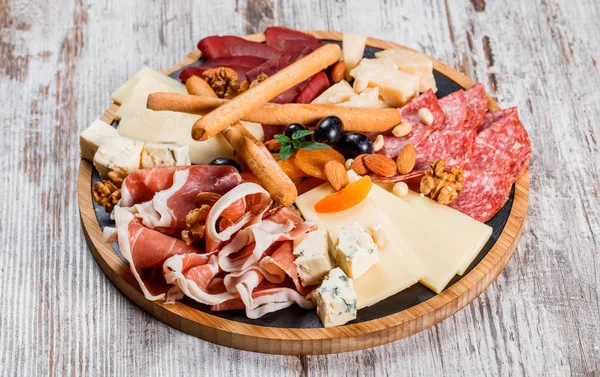Antipasto plakalı soğuk et Grissini ekmek çubukları, Prosciutto, dilim jambon, sığır eti, salam ve peynir tabağı ahşap tahta üzerinde rustik arka plan üzerinde. Aperitif, catering gıda kavramı