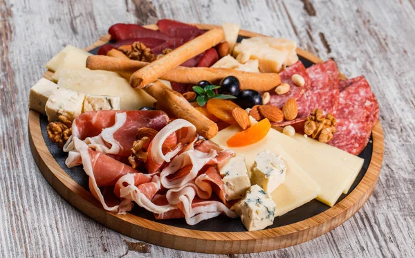 Antipasto tál hideg húst grissini kenyeret botok, prosciutto, szeletek sonka, marhahús szaggatott, szalámi és sajttal tál fából készült hajón rusztikus háttérrel. Előétel, étkezési élelmiszer koncepció — Stock Fotó