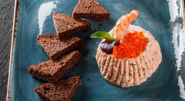 Karides ve kırmızı havyar physalis ve Yeşiller plaka üzerinde süslenmiş siyah arka plan üzerinde siyah ekmek ile snack. Sağlıklı gıda