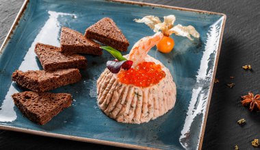 Karides ve kırmızı havyar physalis ve Yeşiller plaka üzerinde süslenmiş siyah arka plan üzerinde siyah ekmek ile snack. Sağlıklı gıda